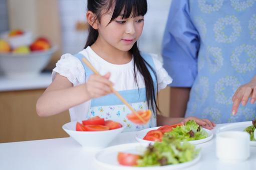 サラダの盛り付けを手伝う女の子 女の子,トマト,野菜の写真素材