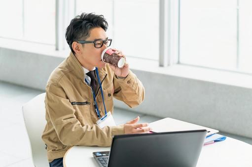 仕事中にドリンクを飲む作業服の男性 仕事中にドリンクを飲む作業服の男性 ビジネス,ビジネスマン,作業員の写真素材