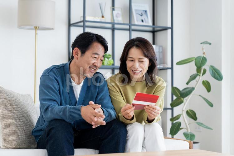 銀行通帳を見るミドルの夫婦 通帳,銀行通帳,夫婦の写真素材