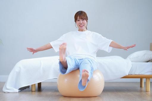 カメラ目線でバランスボールに座りバランスをとる女性 女性,バランスボール,座るの写真素材