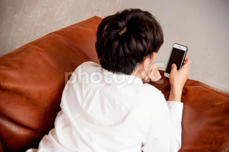 部屋でスマホをみる男性 スマホ,ゲーム,課金の写真素材