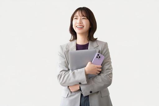 パソコンとスマホを持つ笑顔の女性 女性,笑顔,パソコンの写真素材