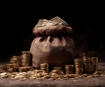 成功の証：山積みのコインとドル札の袋の写真