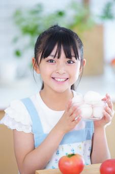 卵を手に笑顔を見せるエプロン姿の女の子 女の子,小学生,日本人の写真素材