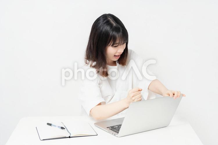 ノートパソコンを使いながら起こっている若い女性 怒る,女性,パソコンの写真素材