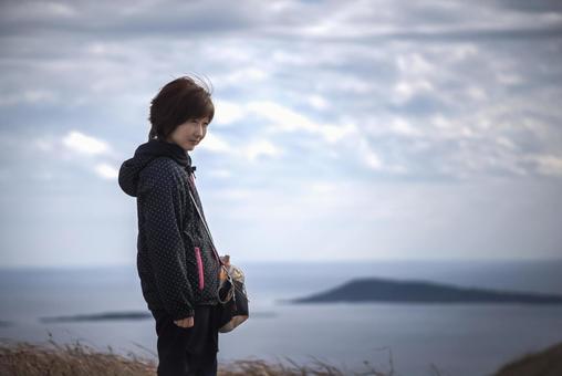 <素材>秋の山の上から海を眺める女性 <素材>秋の山の上から海を眺める女性の写真