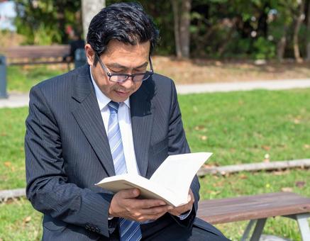 屋外で読書しているサラリーマン 屋外で読書しているサラリーマンの写真