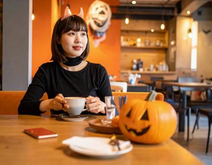 ハロウィンの飾り付けのカフェを楽しむ女性 ハロウィンの飾り付けのカフェを楽しむ女性の写真