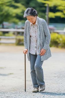 杖を使いながら歩行する女性の姿 杖を使いながら歩行する女性の姿の写真