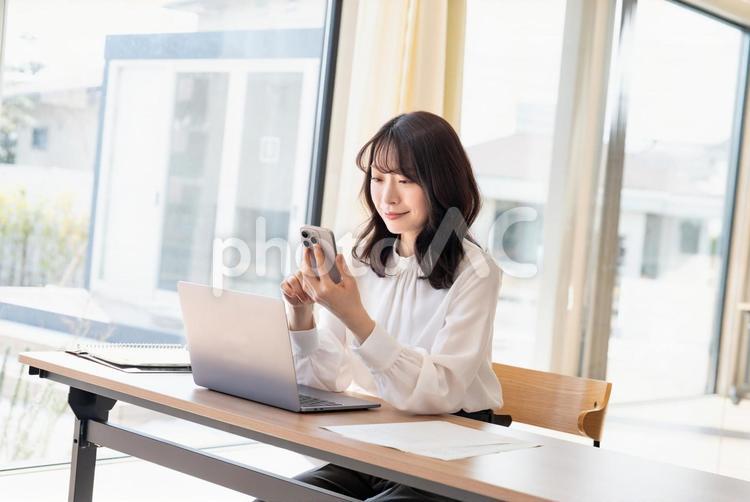 スマホを持つ笑顔の若い女性・ビジネス ビジネスウーマン,女性,スマホの写真素材