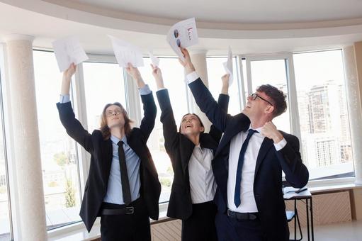 書類を上にあげて持つ外国人男女の写真