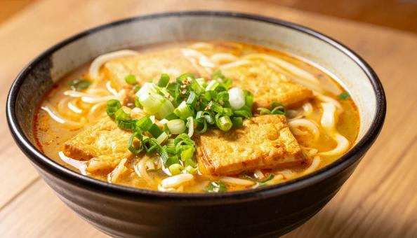 油揚げが乗せられた温かいカレーうどん 油揚げが乗せられた温かいカレーうどんの写真