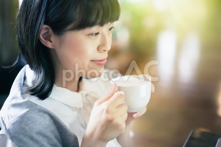 暖かい雰囲気の空間で、コーヒーを飲む若い女性 女性,笑顔,カフェの写真素材