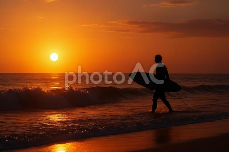 夕暮れの海を歩くサーファーのシルエット 海,サーファー,夕日の写真素材