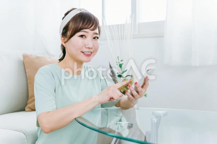 家でスマホを使う笑顔の日本人女性 スマホ,女性,スマートフォンの写真素材