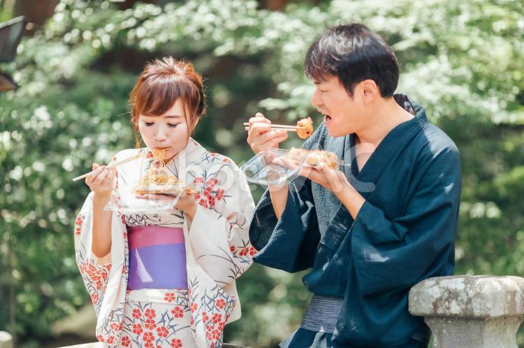 夏祭りにきて焼きそばやたこ焼きを食べる男女 浴衣,夏祭り,夫婦の写真素材