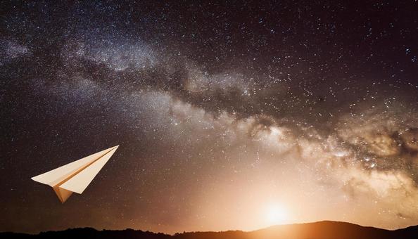 宇宙に向かって飛んでいる紙飛行機の写真