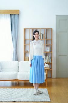 ラグの上に立つ青いスカートの女性 女性,笑う,笑顔の写真素材