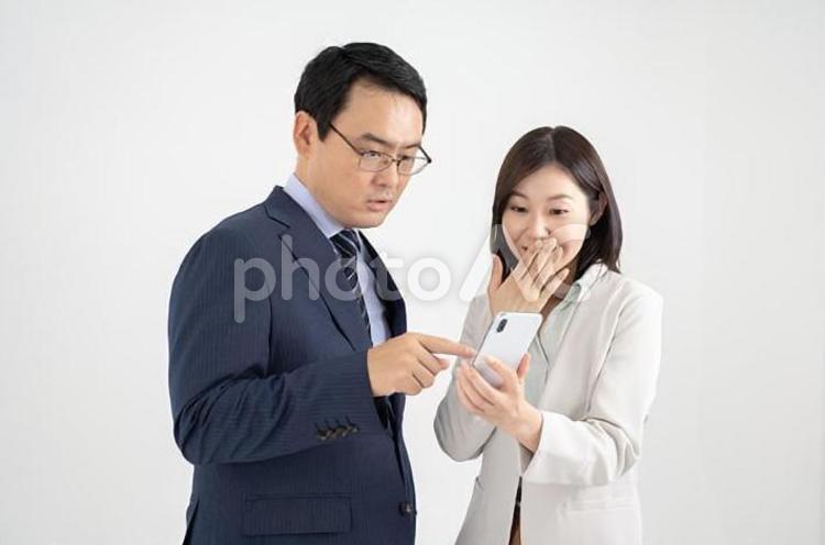 スマホを介して会話する男女のビジネスマン白背景 女性,男性,ビジネスの写真素材