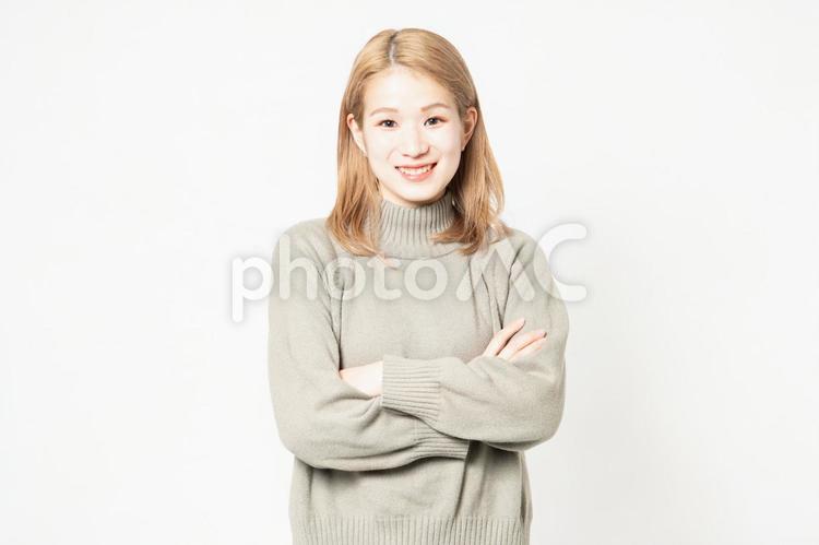 腕を組んで笑っているセーターを着た若い女性 腕組み,女性,腕の写真素材
