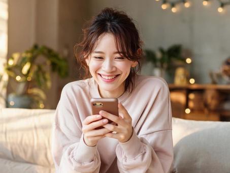 リビングでスマホを見る女性 リビングでスマホを見る女性の写真