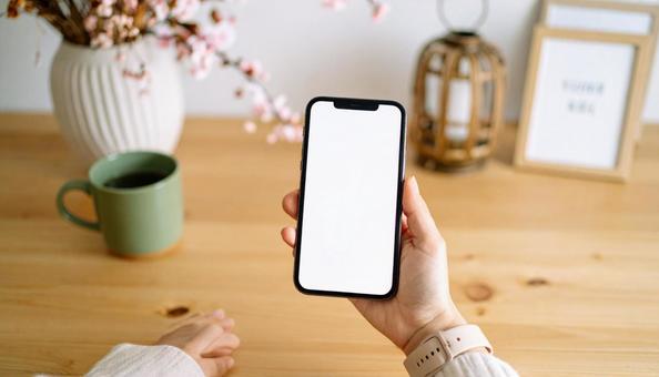 おしゃれなデスクで携帯電話を手に持つ女性 おしゃれなデスクで携帯電話を手に持つ女性の写真