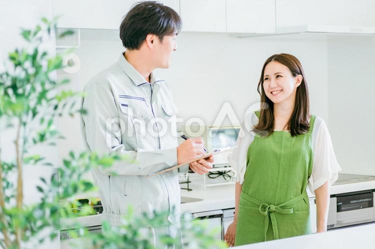 キッチンにいる作業着姿の男性と女性 工務店,点検,メンテナンスの写真素材