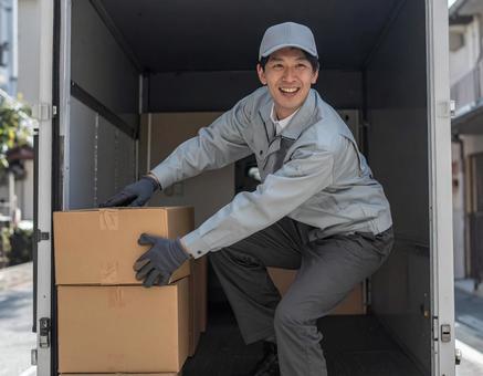 トラックから荷物を出す宅配男性ドライバー トラックから荷物を出す宅配男性ドライバーの写真