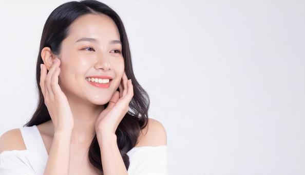 両頬を触り夏のスキンケアをする20代女性 両頬を触り夏のスキンケアをする20代女性の写真