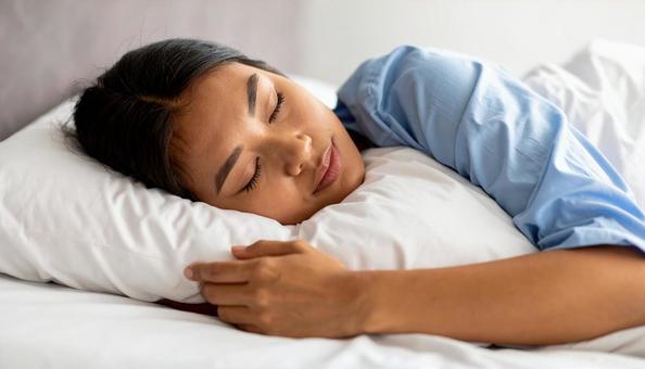 片腕の下にバスタオルを置いて眠る女性患者 片腕の下にバスタオルを置いて眠る女性患者の写真