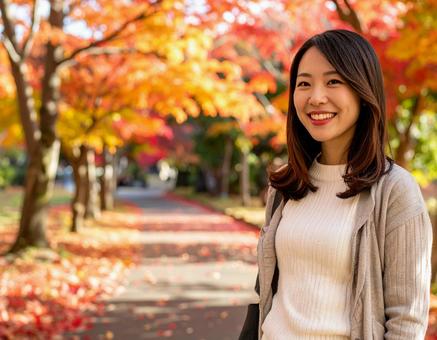 紅葉の道を散歩する女性の写真