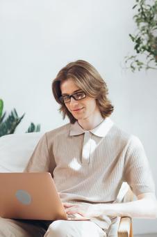 椅子に座って膝の上でノートパソコンを使用する若い男性 男性,外国人,欧米人の写真素材