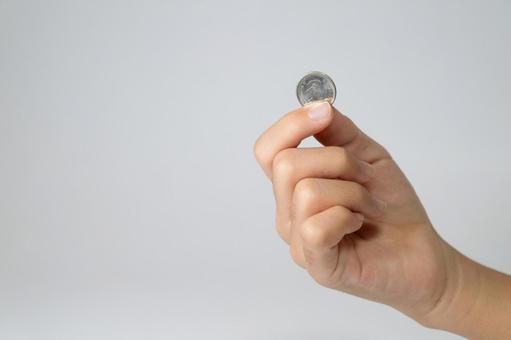 コインをつまむ子供の手のクローズアップの写真
