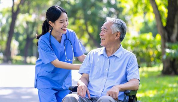 散歩する車椅子の高齢男性と女性介護士 散歩する車椅子の高齢男性と女性介護士の写真