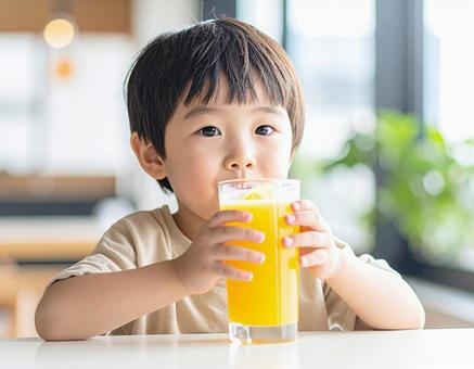 オレンジジュースを飲む子供 オレンジジュースを飲む子供の写真