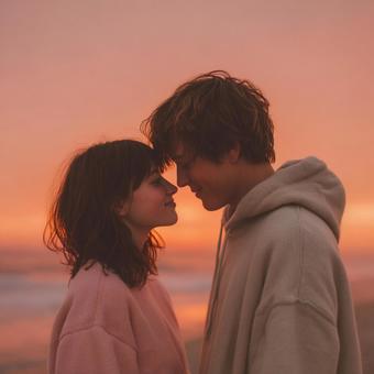 波打ち際で見つめ合う男女カップルの写真