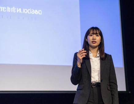 スクリーンの前でプレゼンする女性 スクリーンの前でプレゼンする女性の写真