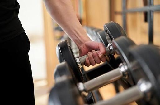 Hands of an Asian man taking dumbbells from a rack Hands of an Asian man taking dumbbells from a rack