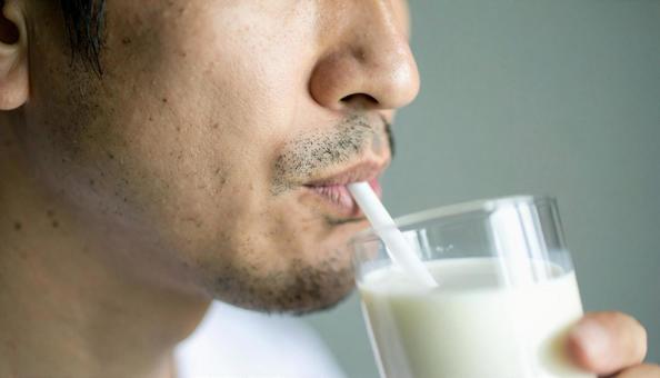 ストローで飲み物を飲むアジア人男性 ストローで飲み物を飲むアジア人男性の写真