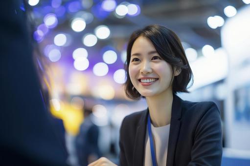 イベントで来場者と話す女性スタッフの写真