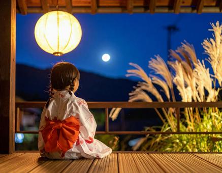 七夕の夜、月を見上げる浴衣の少女の写真
