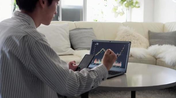 株価の上昇を見て喜ぶアジア人男性 株価,上昇,喜ぶの写真素材