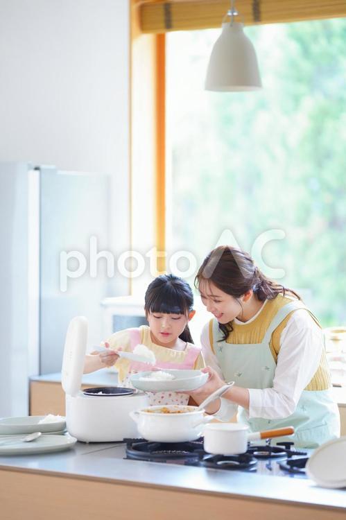 カレーのご飯を盛る女の子 母,娘,炊飯器の写真素材
