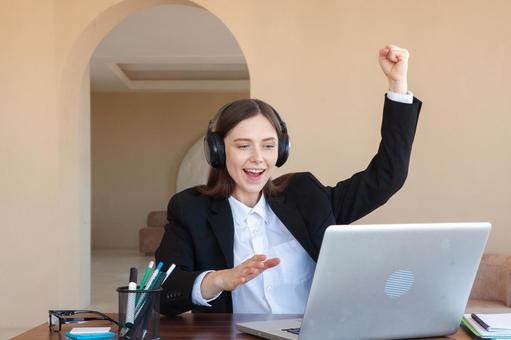 パソコンを見て片手をあげ喜ぶ女性 女性,外国人,ノートパソコンの写真素材