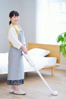 明るい部屋で掃除をする笑顔の女性 明るい部屋で掃除をする笑顔の女性の写真