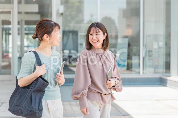ノートを持って話しながら歩くアジア人女性 ビジネスウーマン,話す,ママ友の写真素材