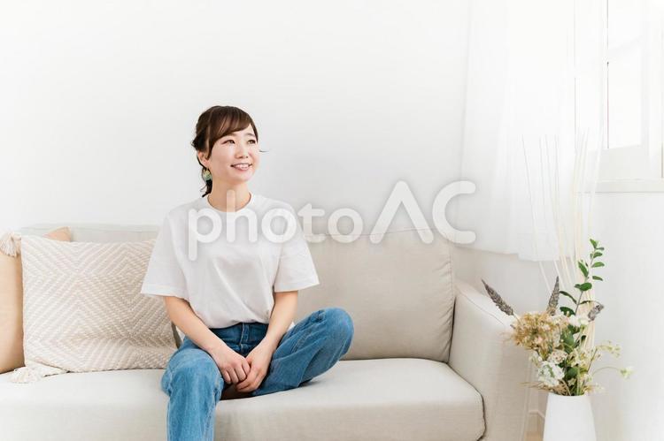 ソファに座る笑顔の日本人女性（紫外線） 女性,笑顔,窓の写真素材