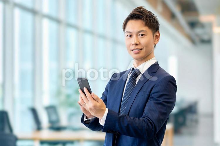 スマホを持つ笑顔の男性ビジネスマン 男性,スマホ,ビジネスの写真素材