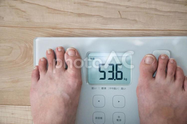 リビングで体重計にそっと足を乗せる女性 体重計,体重管理,健康維持の写真素材