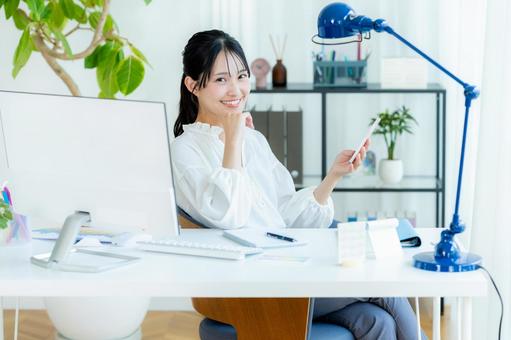 オフィスでスマホを持つビジネスウーマン スマホ,笑顔,ビジネスウーマンの写真素材